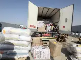 Voluntarios egipcios manejan ayuda humanitaria destinada a los palestinos en la Franja de Gaza, en el cruce fronterizo de Rafah.