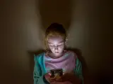 Foto de archivo de una niña mirando el teléfono.