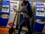 Una mujer entra con un patinete eléctrico en el metro de Ciudad Lineal, Madrid.