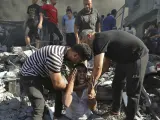 Varias personas consuelan a un hombre que llora después de perder a sus familiares bajo los escombros de una casa destruida tras un ataque aéreo israelí en la ciudad de Gaza.