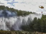 Un helicóptero lanza agua sobre la zona del incendio en Montitxelvo.