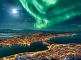 Aurora Boreal y luna llena sobre la ciudad de Tromso.