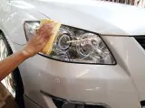 Un conductor limpiando los faros de su automóvil.