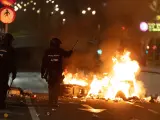 Dos polic&iacute;as frente a una barricada en llamas, con una moto ardiendo, durante los disturbios que se han producido en la manifestaci&oacute;n contra la amnist&iacute;a en diferentes puntos del centro de Madrid.