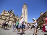 Un grupo de turistas pasean junto a la Catedral de Sevilla, en la plaza Virgen de los Reyes.