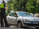 Un policía municipal multa a un coche con matrícula portuguesa.