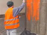 Un activista de Letzte Generation mancha con pintura naranja una columna de la Puerta de Brandeburgo.