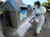 Una trabajadora de Lipasam realizando baldeos con agua a presión para limpiar los contenedores