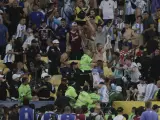 Varios aficionados con los brazos en alto, en las grada de Maracaná, mientras la policía intentan controlar la trifulca entre varios seguidores de Brasil y Argentina.