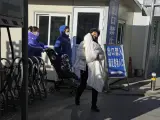Una mujer carga a un ni&ntilde;o al salir de un hospital infantil en Beijing.