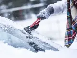 Mujer elimina nieve y hielo de la luna del coche.