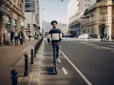 Un joven pilotando su patinete eléctrico por la calles de una ciudad.