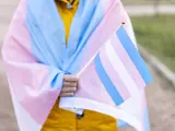 Mujer transgénero cubierta con la bandera transgénero