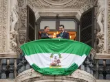 El presidente de la Junta de Andalucía, Juanma Moreno, y la bailaora Sara Baras despliegan la bandera de Andalucía en el balcón principal de San Telmo.