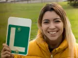 Una joven posa sonriente con la L tras aprobar el examen de conducir.