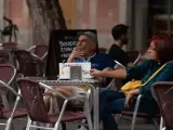 Una pareja sentada en la terraza de un bar fumando.