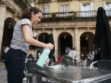 Una camarera limpia una mesa en la terraza de un bar en el centro de Bilbao (archivo).