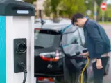 Man plugging in charger into an electric car at charge station
