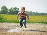Un niño salta sobre un charco de agua