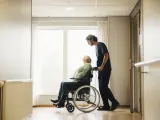 Enfermero asisten a una persona en silla de ruedas.