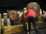 Dos operarios colocan los bombos que repartir&aacute;n la suerte del Sorteo Extraordinario de la Loter&iacute;a de Navidad 2023, que se celebra en el Teatro Real de Madrid.