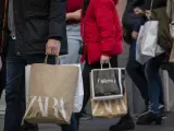 Varias personas con bolsas de la compra en una calle céntrica.