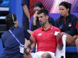 Novak Djokovic siendo atendido por el fisio durante su partido ante De Miñaur en la United Cup.
