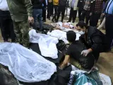 Hombres iraníes junto a algunos cuerpos de los muertos en el atentado de este miércoles en Irán.