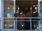 Dos personas con una mascarilla en la cara conversan a su salida de un centro de salud en la Comunidad de Madrid.
