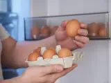 Hombre pone huevos frescos en la nevera.