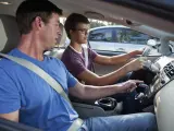Un adolescente al volante de un coche con su padre de copiloto.