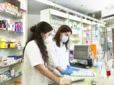Mujeres j&oacute;venes con mascarilla trabajando en farmacia