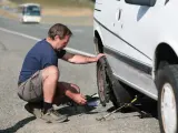 Un conductor cambia el neumático que ha sufrido un reventón por culpa del estado de la carretera.