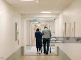 Una persona mayor pasea por un centro acompañado de una trabajadora.