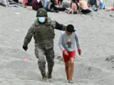 Un militar del ejército español acompaña a un niño migrante en Ceuta.