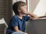Un niño mira con gesto triste por la ventana