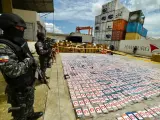 Policías antinarcóticos ecuatorianos montan guardia junto a paquetes de cocaína de un cargamento de 3 toneladas incautado en un contenedor de plátanos, en el puerto de Guayaquil, Ecuador, el 1 de abril de 2022.