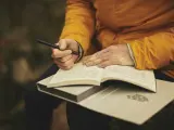 Una persona escribiendo en un cuaderno.
