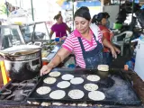 Una mujer prepara pupusas en un mercadillo de El Salvador.