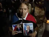 Un simpatizante del fallecido presidente chileno Sebastián Piñera sostiene fotos suyas en el patio de la sede del partido político Renovación Nacional, en Santiago de Chile, el martes 6 de febrero de 2024.