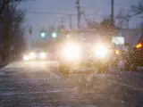 Car driving on snowy urban street at night