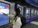 Una mujer compra su billete en una pantalla táctil en la estación de metro de Gran Vía