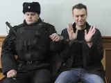 El líder de la oposición rusa Alexei Navalny, a la derecha, posa para la prensa mientras está sentado esposado en un tribunal en Moscú, en marzo de 2017.