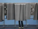 Un hombre utiliza una cabina de votación en un colegio electoral de Ames.