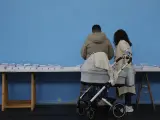 Una pareja joven escoge una papeleta para ejercer su derecho al voto en un colegio de Ames.
