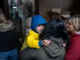 Marina sostiene a su hija Maria, de 4 años, en el punto de distribución de ropa de invierno de UNICEF.