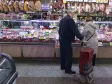 Una pareja compra en una charcutería en un mercado.