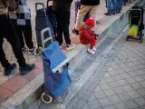 Un niño espera a recibir un regalo de Navidad en una cola de reparto solidario.