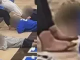 Dos capturas del vídeo donde se ve a los alumnos lamer los pies de un grupo de adultos.