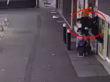 Una mujer se apoya en una verja y acaba siendo levantada por los aires mientras una cámara de seguridad le graba